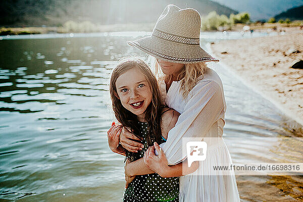 Mutter und Tochter  die sich umarmen und lächeln  während sie in einem See stehen