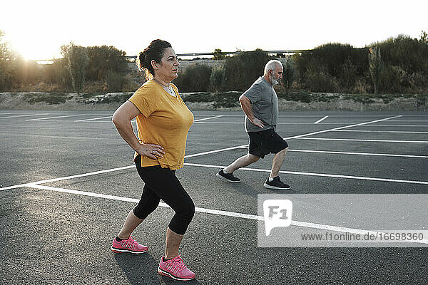 A middle-aged couple are working out on the street