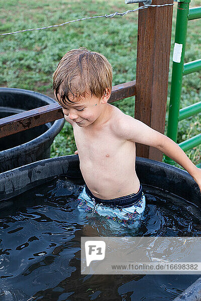 Little boy standing in the horse trough