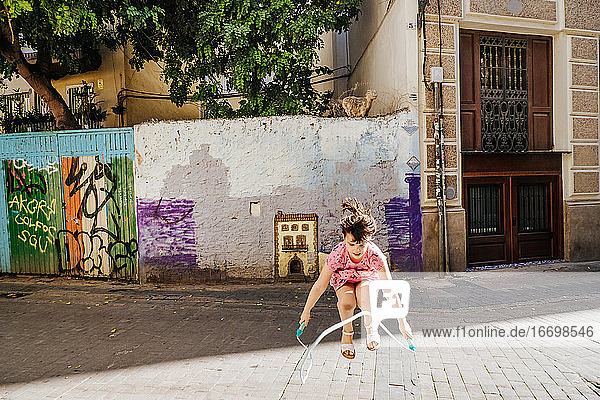 Young girl playing with a skipping rope in a colorful street