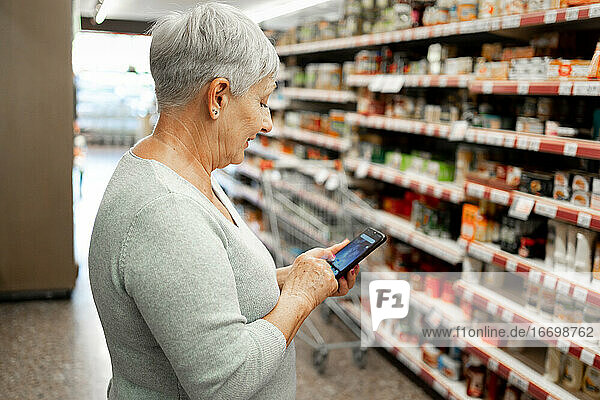 Caucasian elderly woman with white hair shopping in supermarket