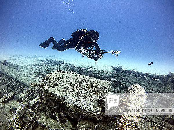 Underwater diving photographer taking pictures over an old wreck