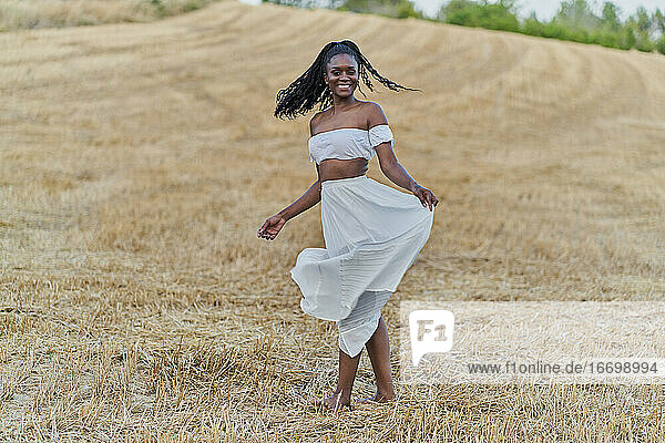 Fotosession einer schönen schwarzen Frau in einem Weizenfeld mit einem weißen Kleid