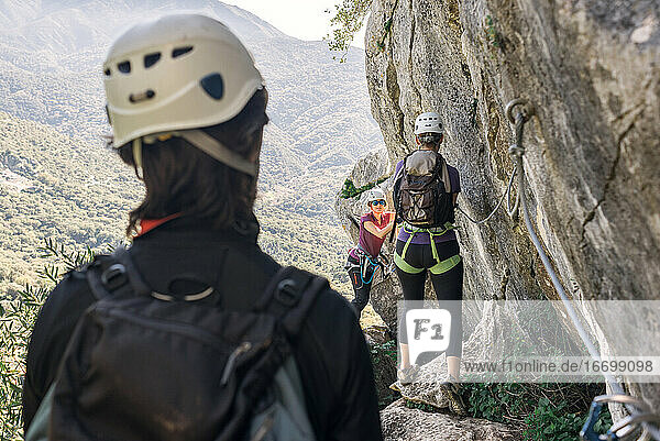 Konzept: Abenteuer. Zwei Frauen und ein Mann in den Bergen mit Helm  Klettergurt  Rucksack und Ausrüstung für den Klettersteig.