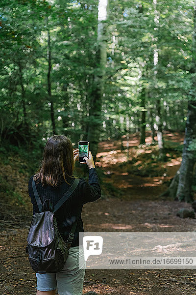 Mädchen fotografiert mit ihrem Mobiltelefon in einem Wald