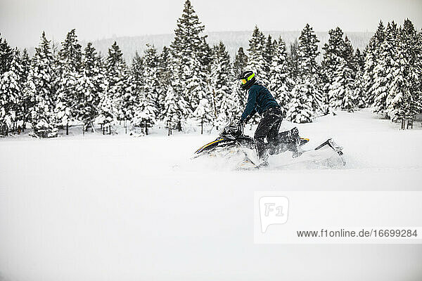 Seitenansicht eines Mannes beim Schneemobilfahren an einem verschneiten Tag.