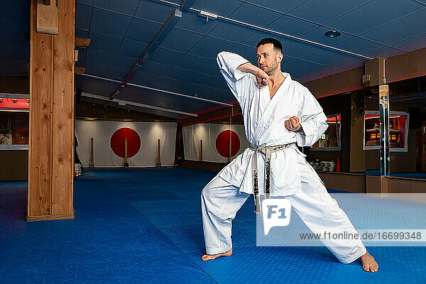 Karate-Mann steht auf der Tatami und macht 'Empi Waza'