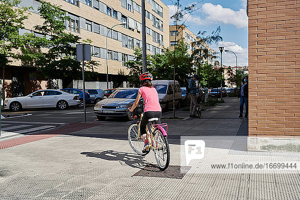 Mädchen  das auf einer leeren Straße in seinem Viertel Fahrrad fährt  trägt Fa