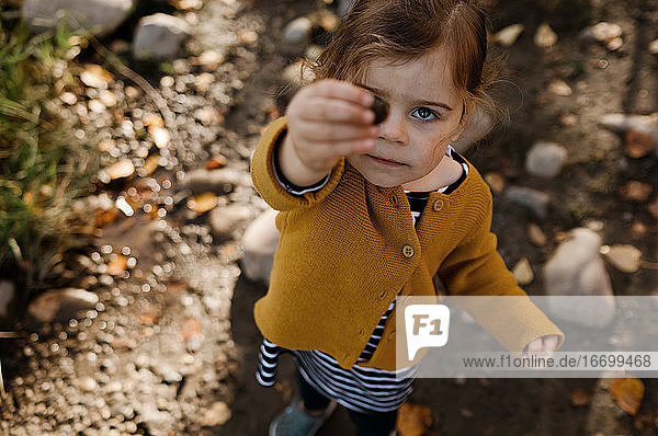 Junges Mädchen hält einen Stein hoch  der ihr Auge bei einem Sturz verdeckt