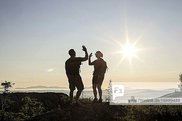 Zwei Wanderer geben sich die Hand und feiern das Erreichen des Gipfels eines Berges  Maine