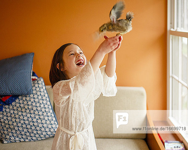 Ein Kind lacht vor Freude und hält einen flatternden Vogel in den Händen