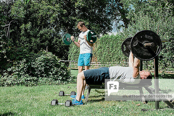 zwei Männer trainieren gemeinsam in einem Fitnessstudio im Garten