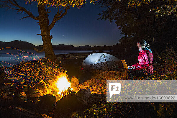 Frau arbeitet am Laptop in einem Camp am Nahuel Huapi See in Patagonien