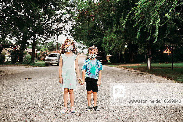Zwei junge Kinder stehen draußen und tragen selbstgemachte Stoffmasken