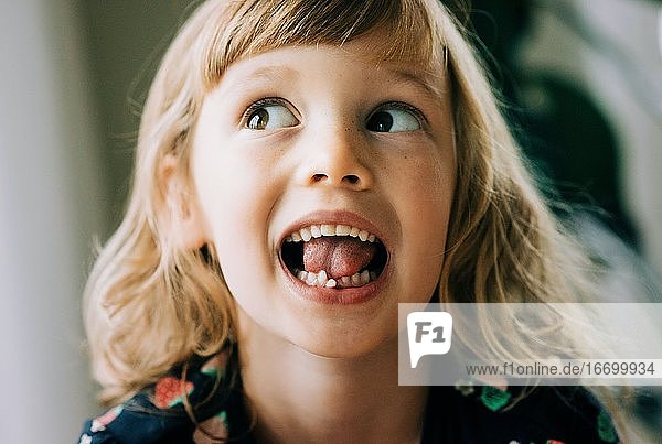 junges Mädchen mit wackeligen Zahnziehen Gesichter zeigen ihren Zahn