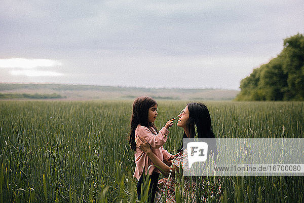 Lächelnde Mutter und Tochter  die sich auf einem Feld unterhalten