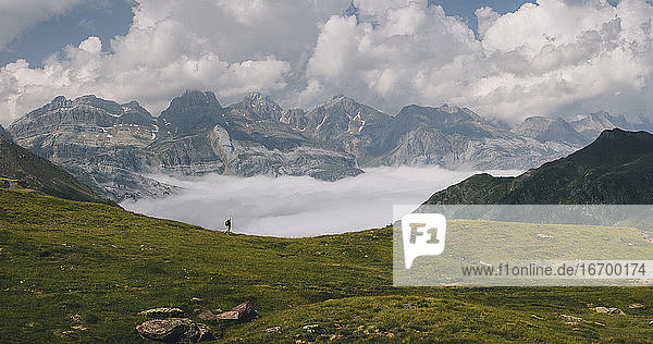 Young woman hiking through Pyrenees with Mount Aspe in the background.