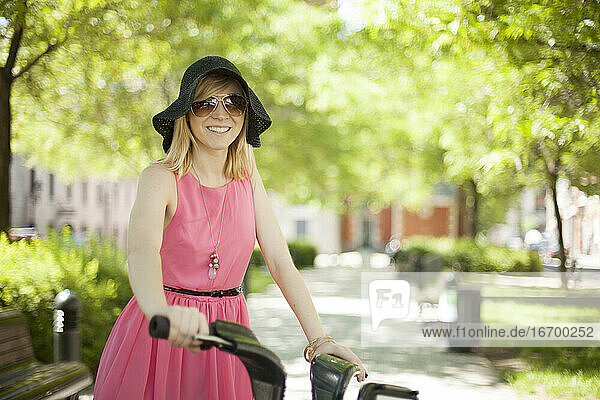 Frau im rosa Kleid fährt Fahrrad im Park