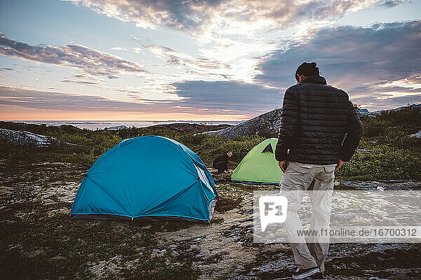 2 men in campsite at sunset on cloudy sky