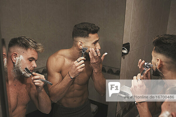 A couple of gay guys are shaving together in the bathroom at home