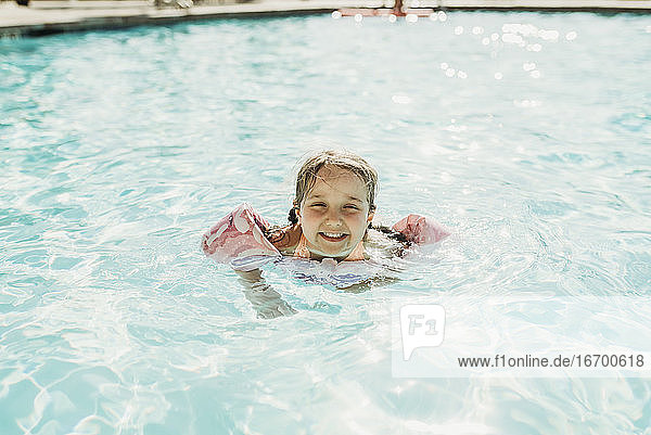 Young preschool age girl swimming in pool on vacation in Palm Springs