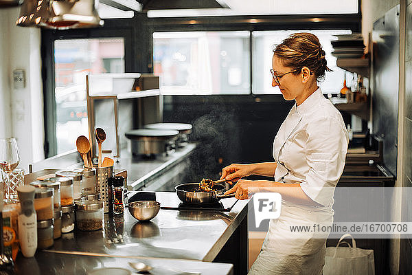 Weibliche Köchin  die in der Restaurantküche heiße Speisen umrührt