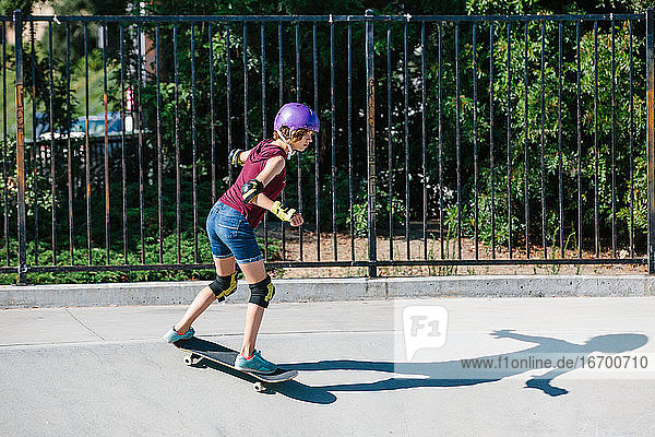 Teenager-Skaterin skatet in einem Skatepark und trägt dabei Schutzkleidung