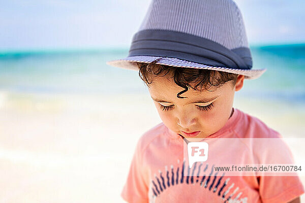 Little boy with curly hair walking a the beach in the Caribbean