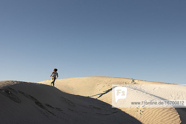 One kid runs on the ridge of a dune at Dunas de la Soledad