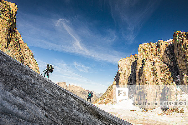 Backpackers hiking up glacier  ascending Mount Asgard  Baffin Island.