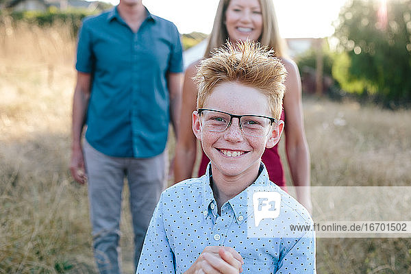 Rothaariger Junge lächelt  während er eine überdimensionale Brille trägt