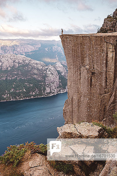 Mann steht und blickt auf den Rand einer Klippe am Preikestolen  Norwegen