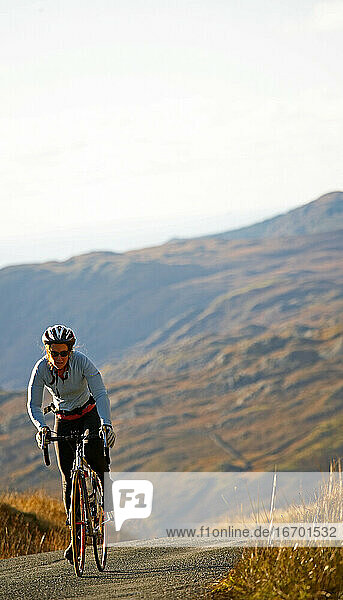 female cyclist approaching top of a hill at the British Lake district