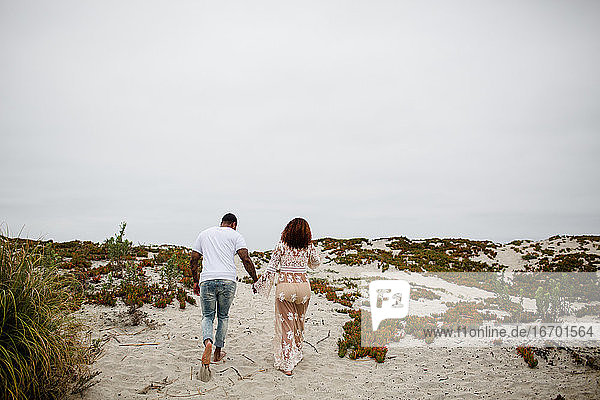 Mixed Race Couple Holding Hands Walking on Beach