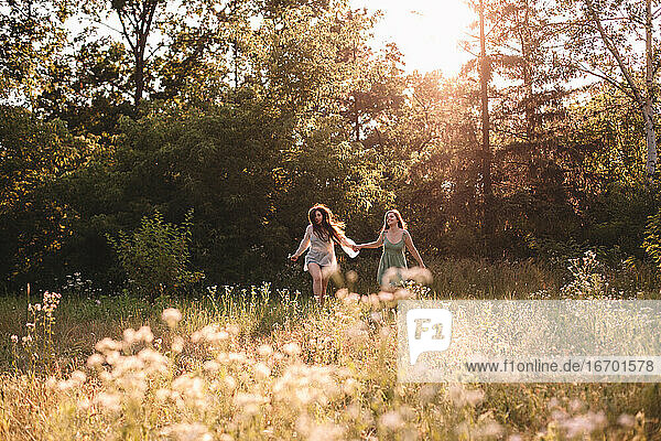 Glückliches lesbisches Paar hält Hände beim Laufen im Wald im Sommer