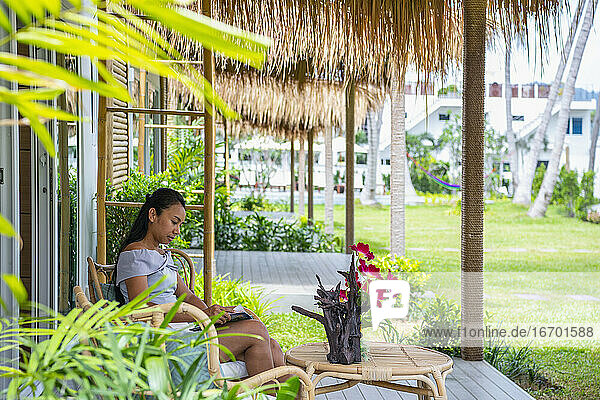 lesende Frau vor einem Ferienhaus in Phuket