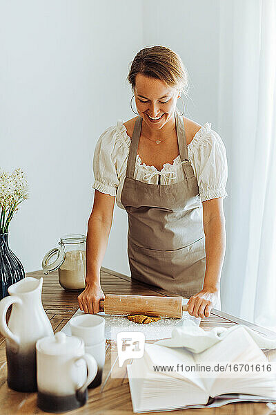Frau rollt Teig für Kekse in der heimischen Küche aus