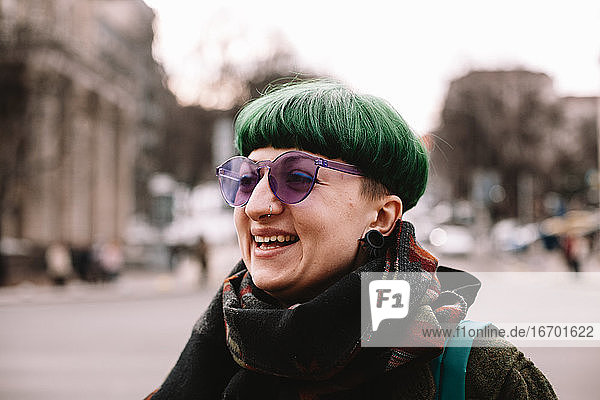 Porträt einer glücklichen Punkerin mit lila Sonnenbrille in der Stadt stehend