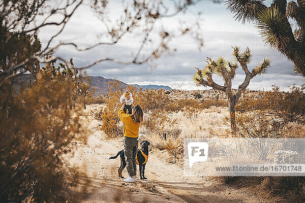 Eine Frau mit einem Baby und einem Hund steht in der Wüste von Kalifornien
