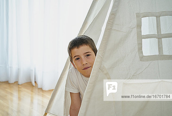 Junge schaut durch ein Fenster auf ein weißes Tipi-Zelt. Kreatives Konzept