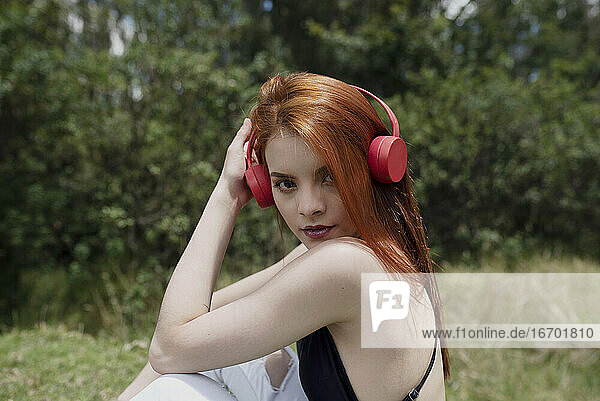 cute red hair girl listening music in the park