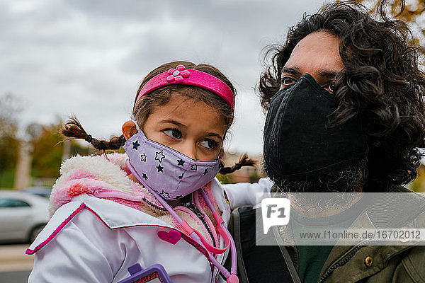 Vater und Tochter mit Schutzmasken und Halloweenkostüm