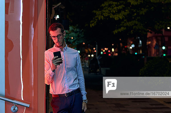 Junger Geschäftsmann schaut nachts auf sein Telefon. Entrepreneur  Bus