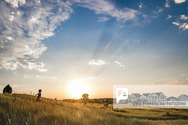 young girl runs down a grass hill at sunset in a surbub neighborhood