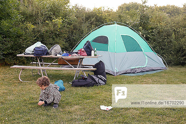A little boy in pajamas outside a camping tent