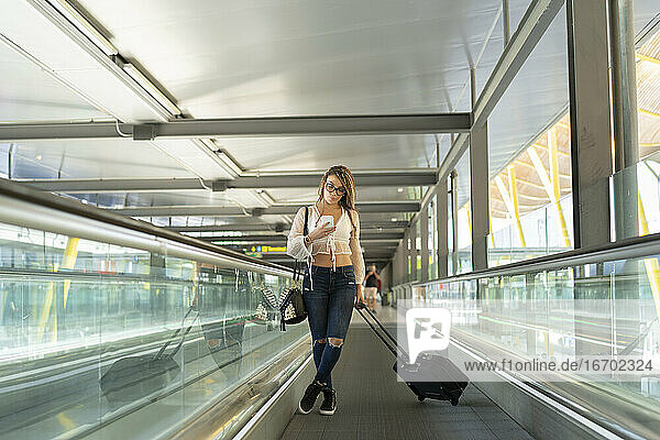 Tourist am Flughafen  der sein Smartphone benutzt  bevor er seinen Flug antritt