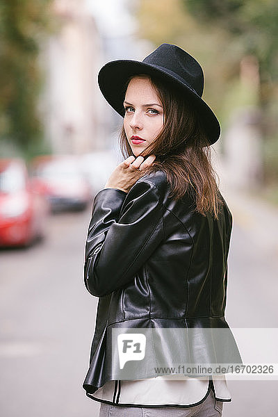 Porträt einer jungen Frau im Freien mit schwarzem Hut und Lederjacke
