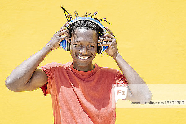 Fröhlicher schwarzer Mann setzt Kopfhörer auf