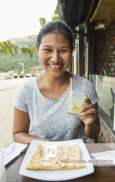 Frau genießt ein Getränk und einen Snack auf der tropischen Insel Ilha Grande