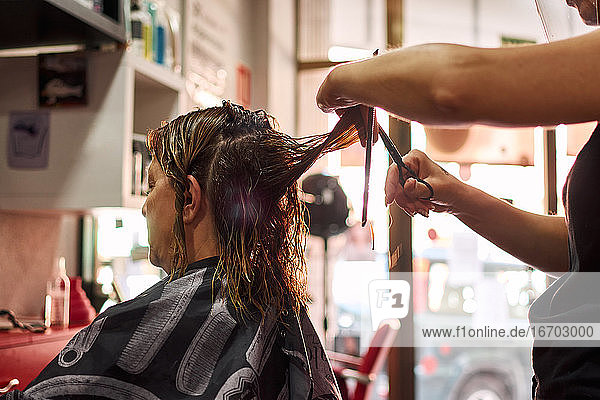Eine Nahaufnahme eines Friseurs  der einem Kunden die Haare schneidet. Kleines Geschäft